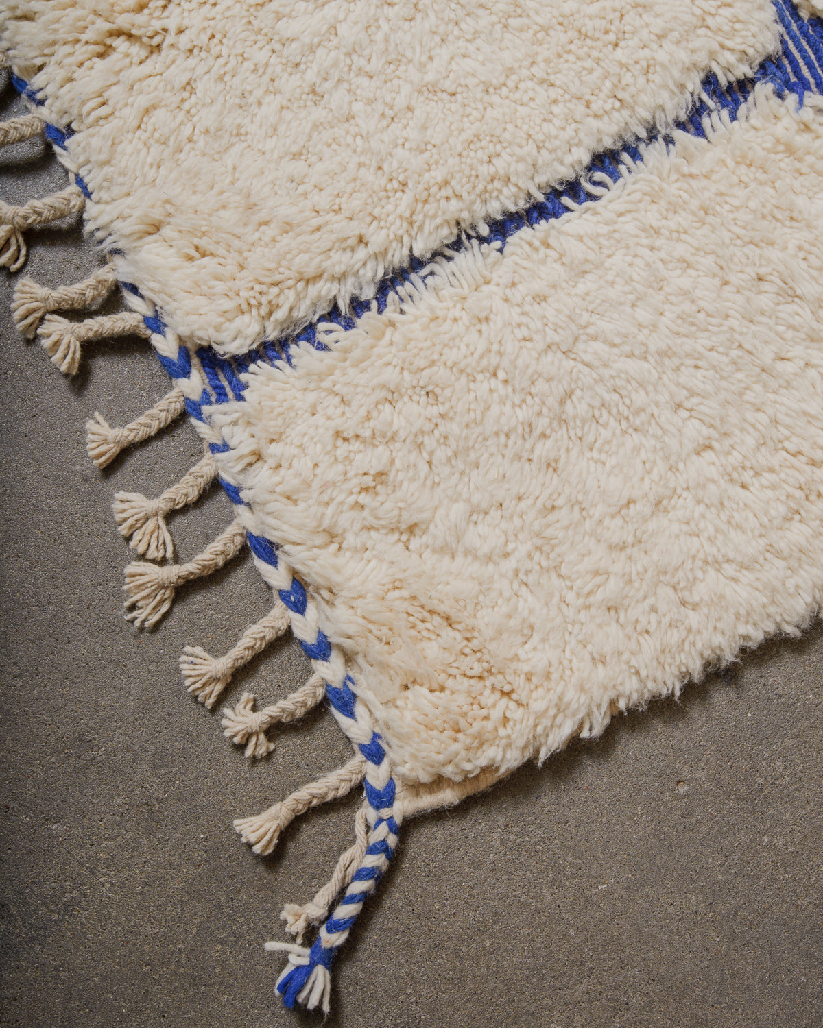 Close-up of a textured rug with blue and cream wool.