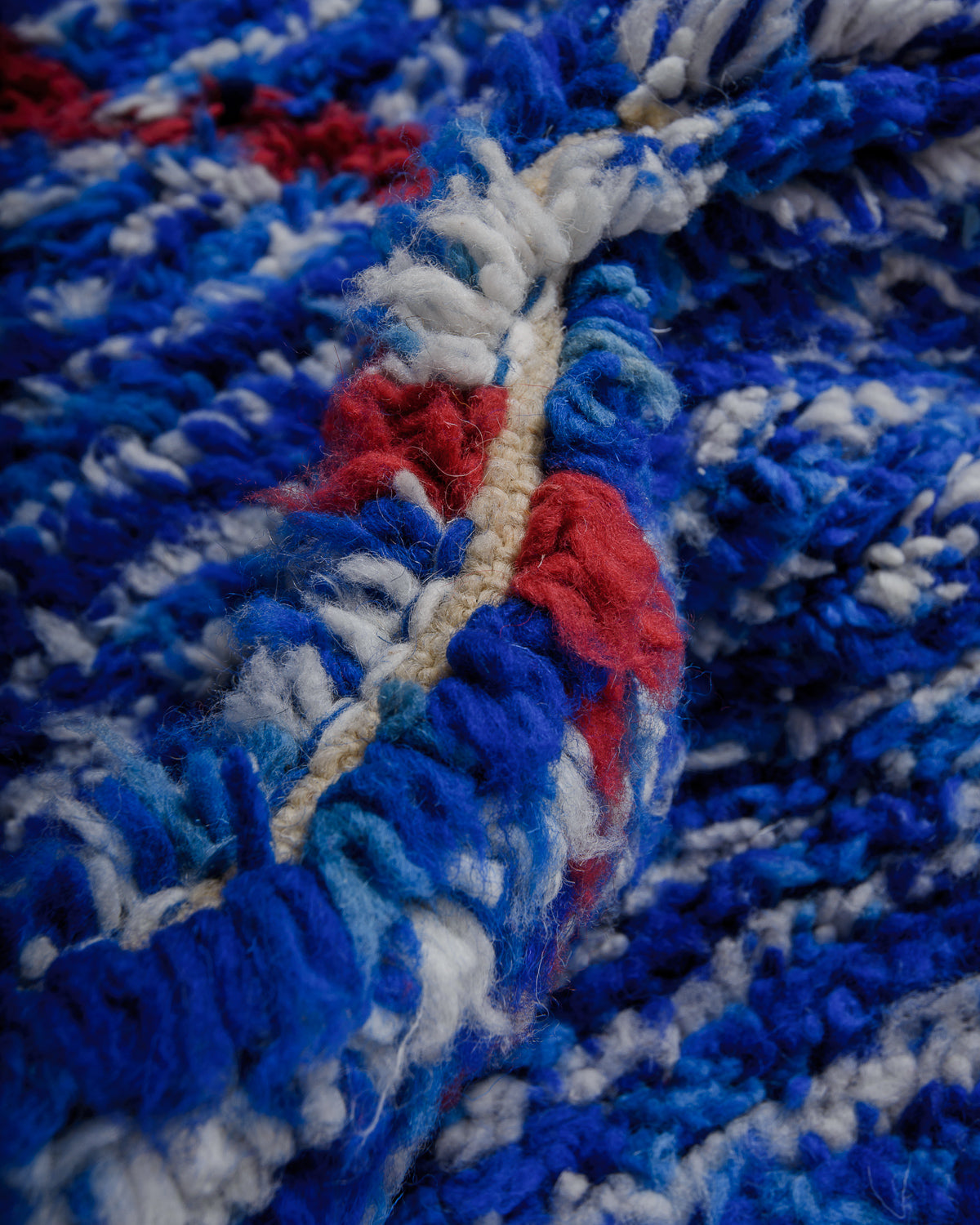 Close up of speckled blue rug with maroon details. 