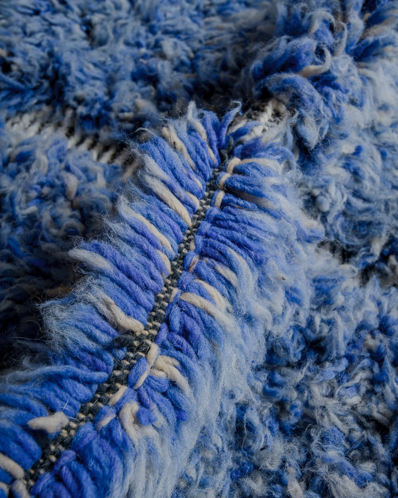 Close up of beniourain rug with thick blue pile made up of strands of blue and white wool.