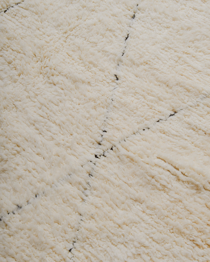 Close up of surface of cream wool rug with black lines.