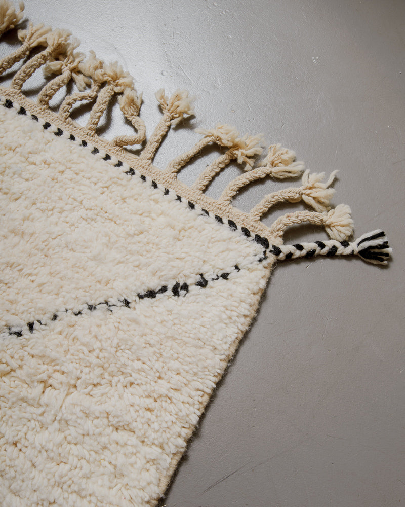 Corner of wool rug with natural tassels.