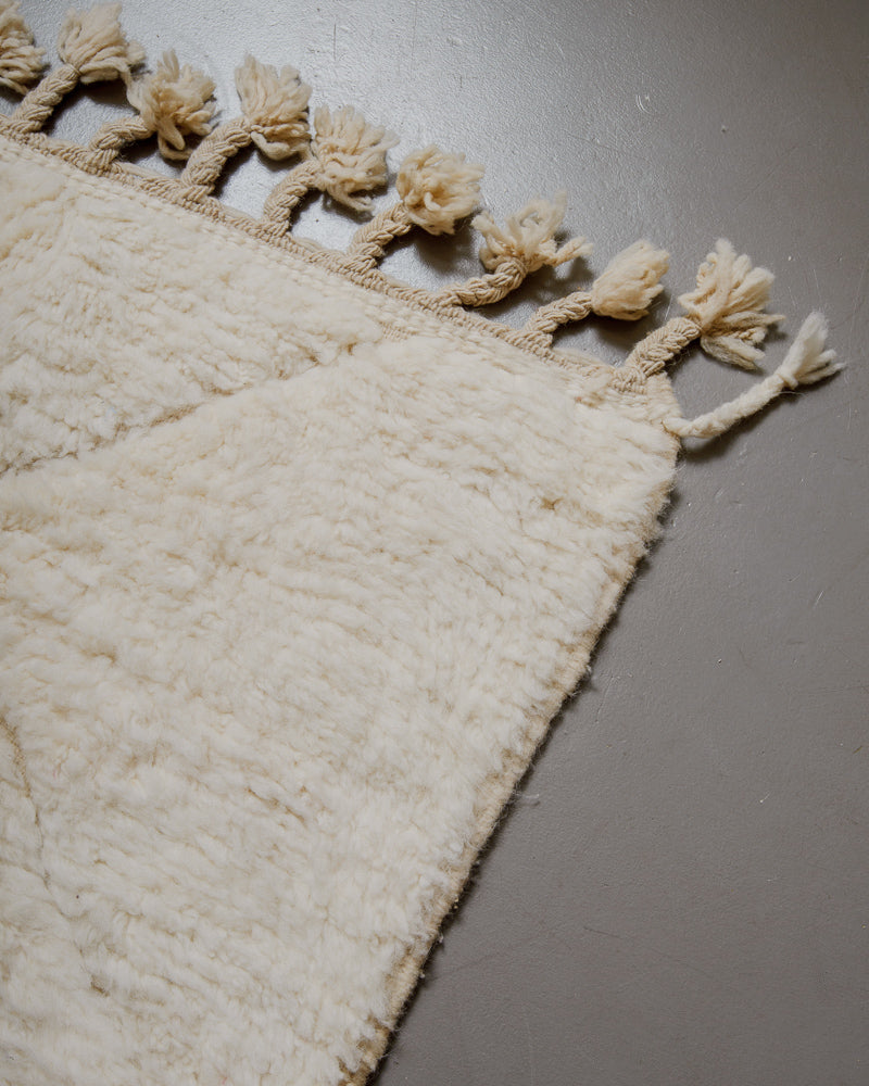 Corner of wool rug with natural tassels.