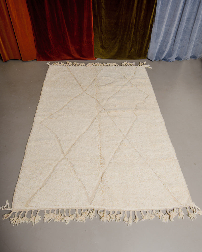 Berberlin Beniourain rug in cream wool on grey floor.