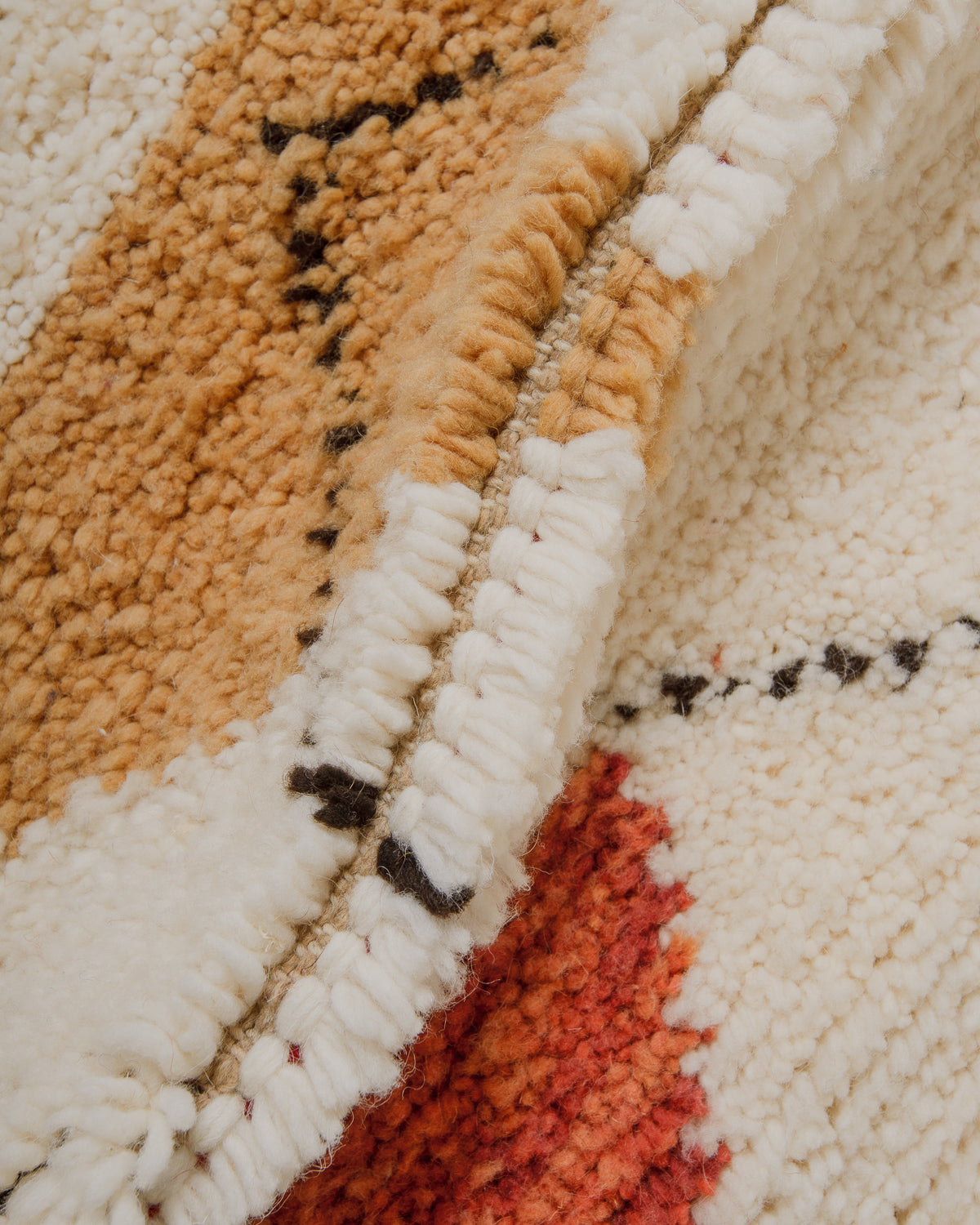 Close up of wool beniourain rug with cream, camel and rust brown wool.