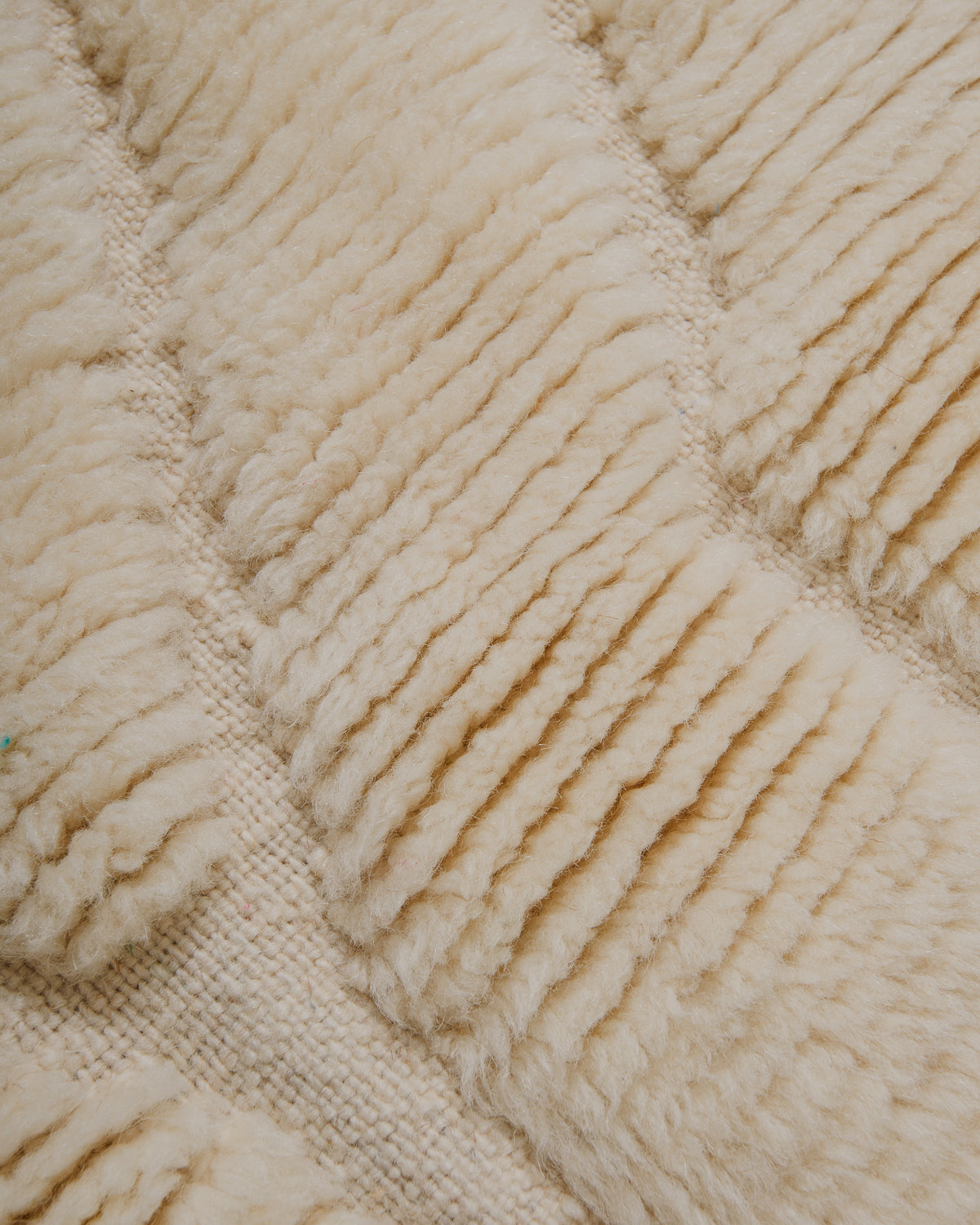 Close up of cream wool rug with soft pile and woven areas. 