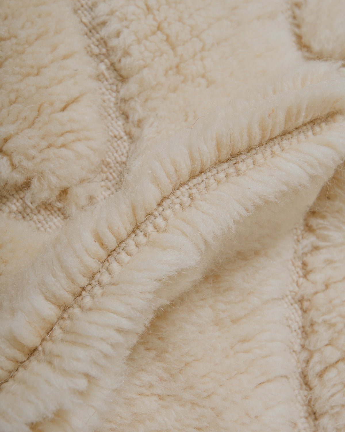 Close-up of cream wool rug with thick pile and flat-woven design.