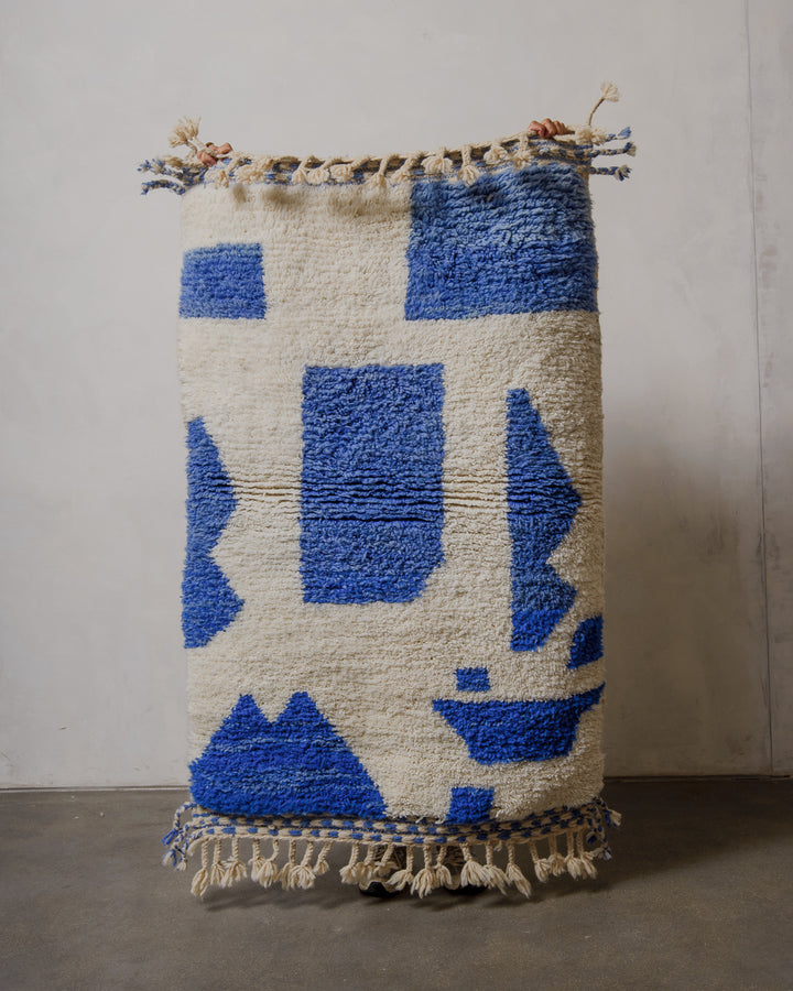 Rug with blue and cream geometric pattern on a plain background