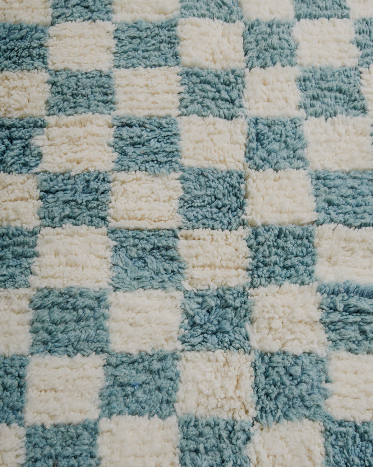 Close up of surface of checkered wool rug in cream and robin's egg blue.