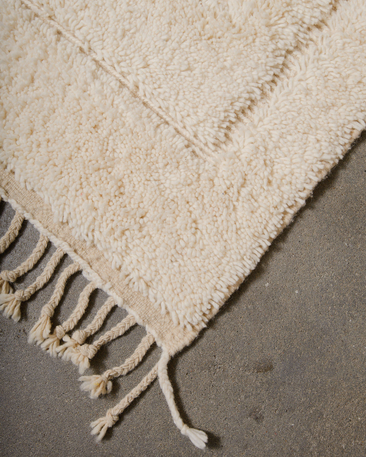 Corner of cream Berber rug with natural wool tassels.