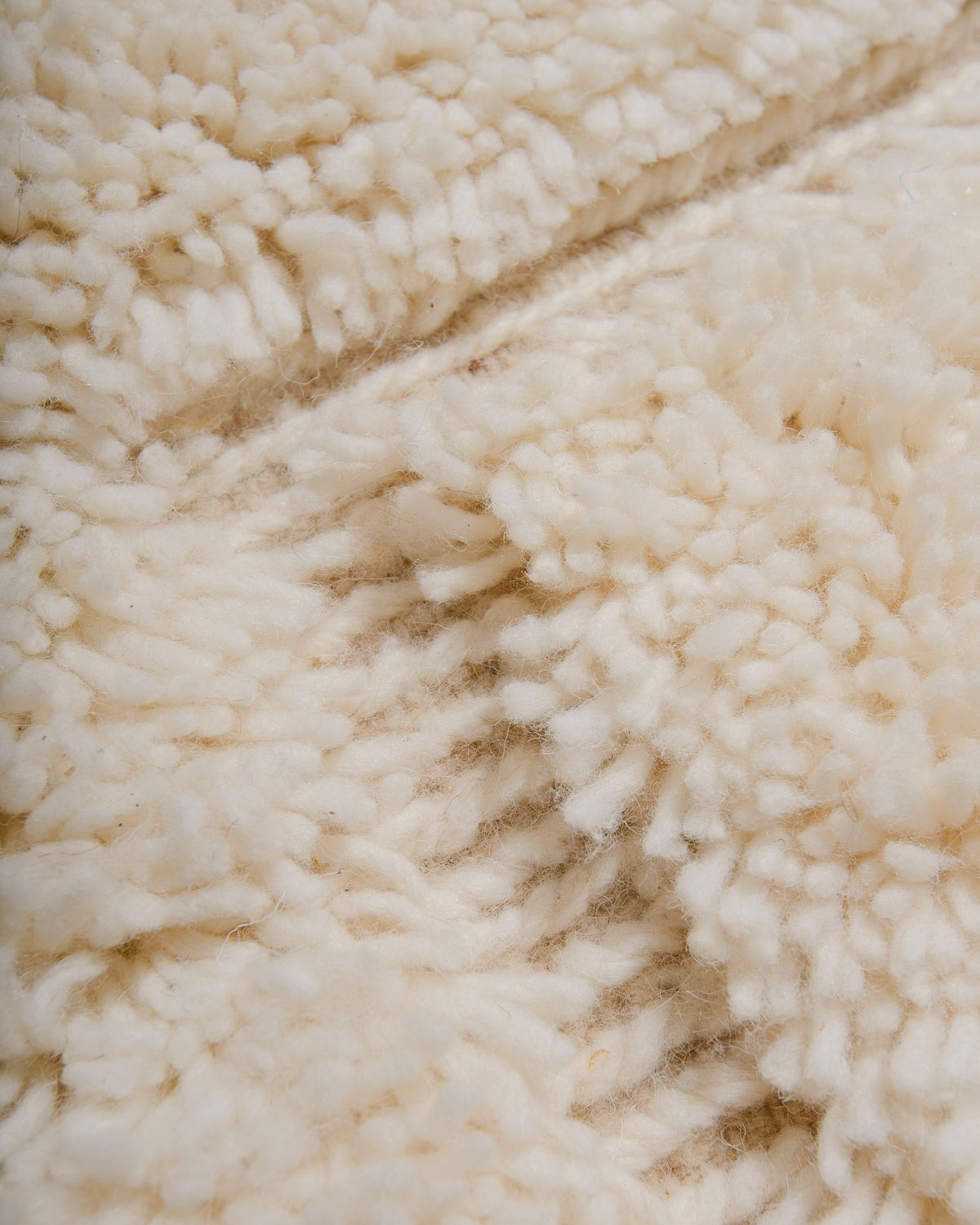 Close up of fluffy cream wool pile of Beniourain rug.