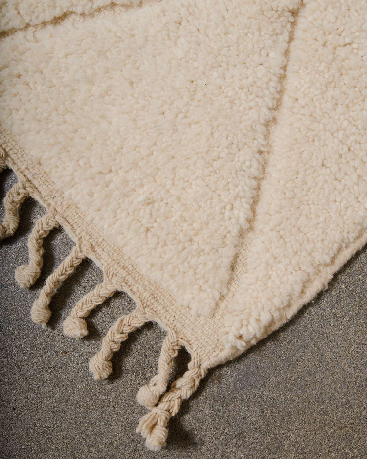 Corner of cream Berber rug with natural wool tassels.