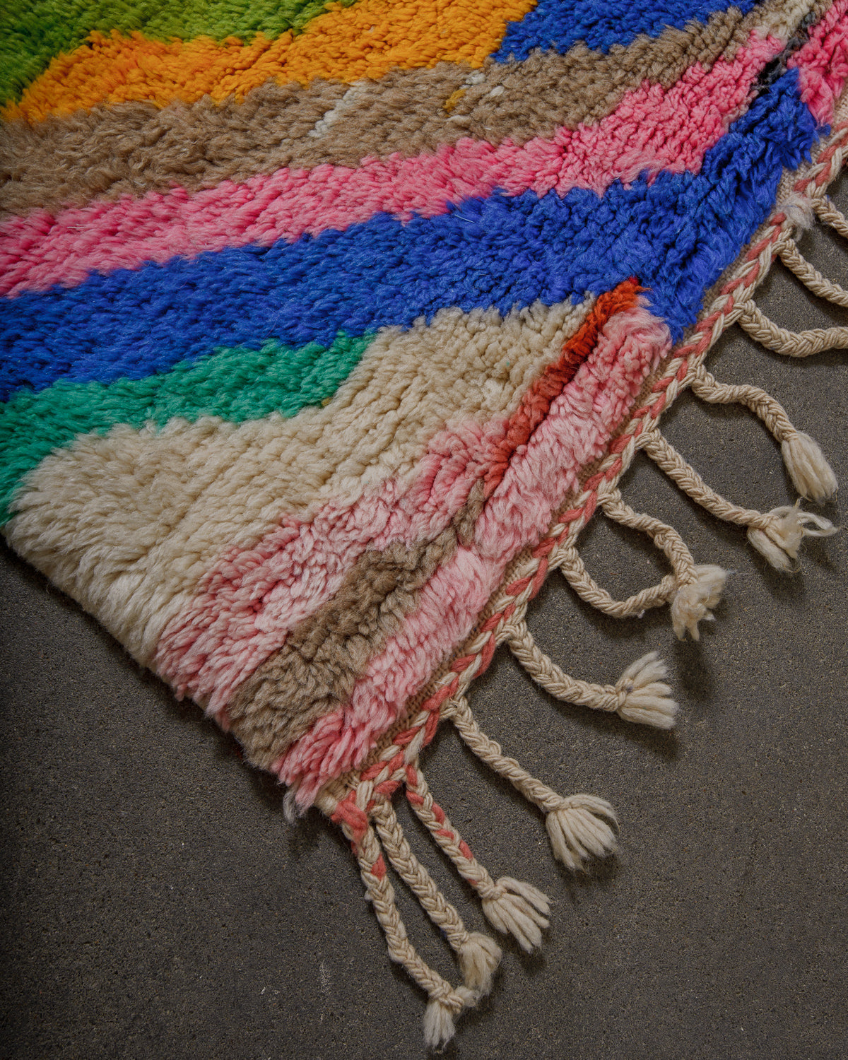 Colorful woven rug with fringe on a dark surface