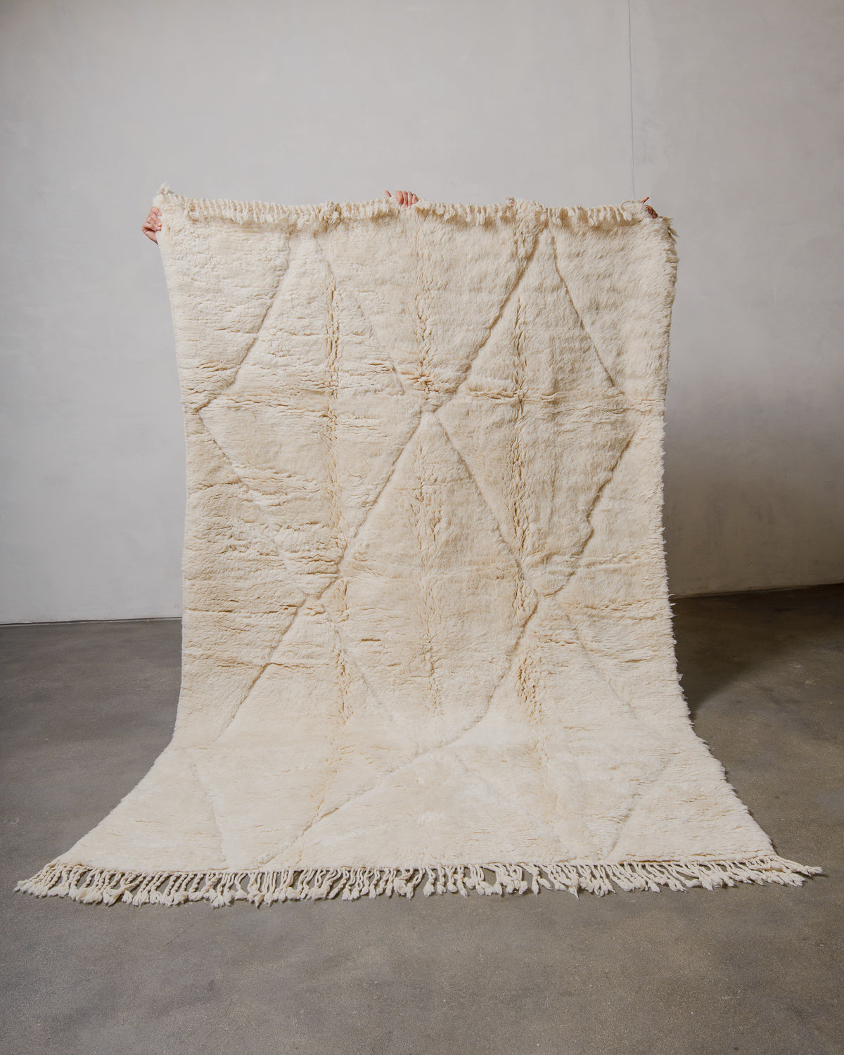 Textured beige rug with diamond pattern on a plain background