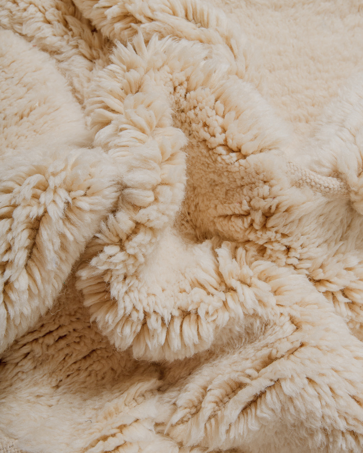 Close-up of cream wool rug with fluffy, velvety surface .