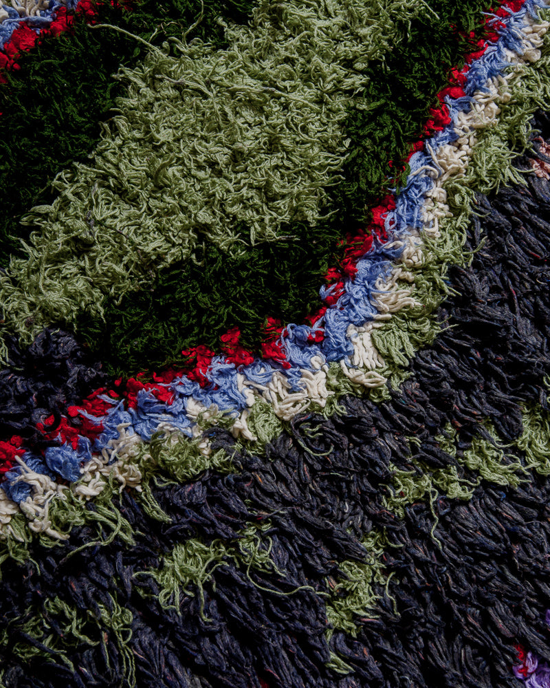 Close up of boucherouite rug with cotton in shades of green, blue and red.