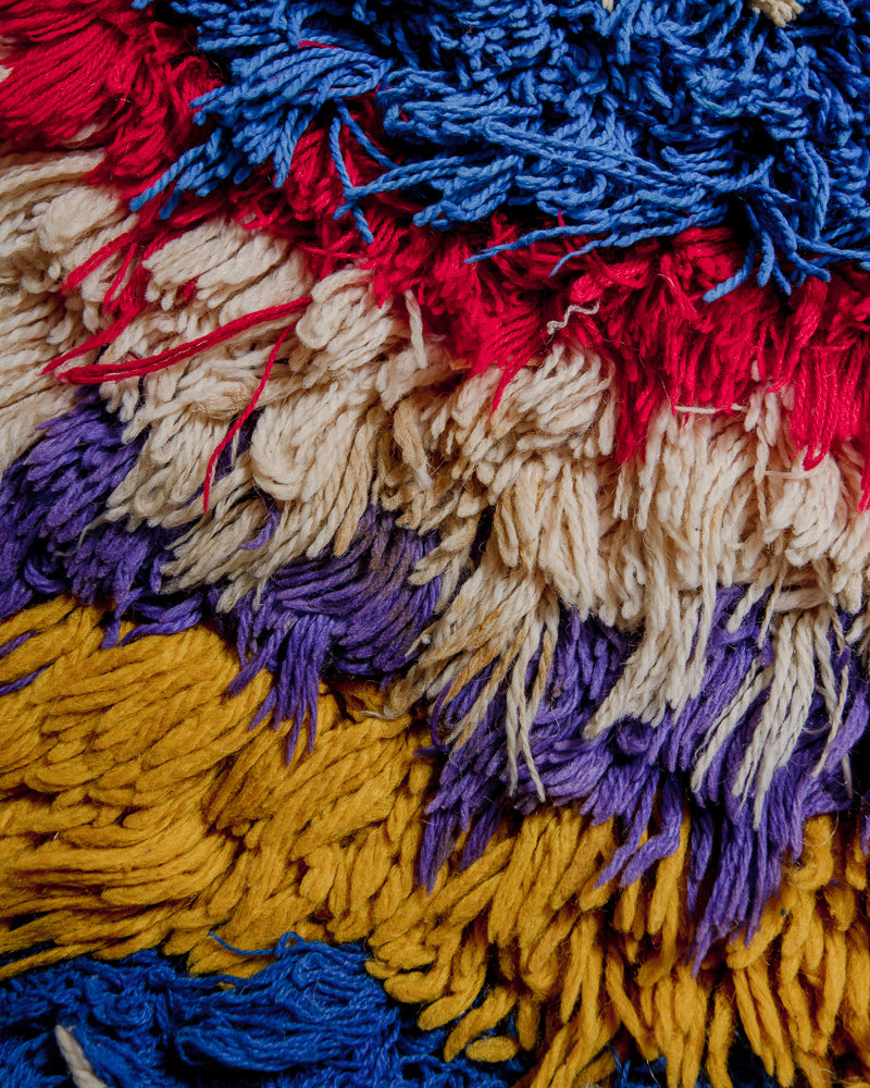Close up of boucherouite rug with cotton in shades of yellow, purple, blue and red.