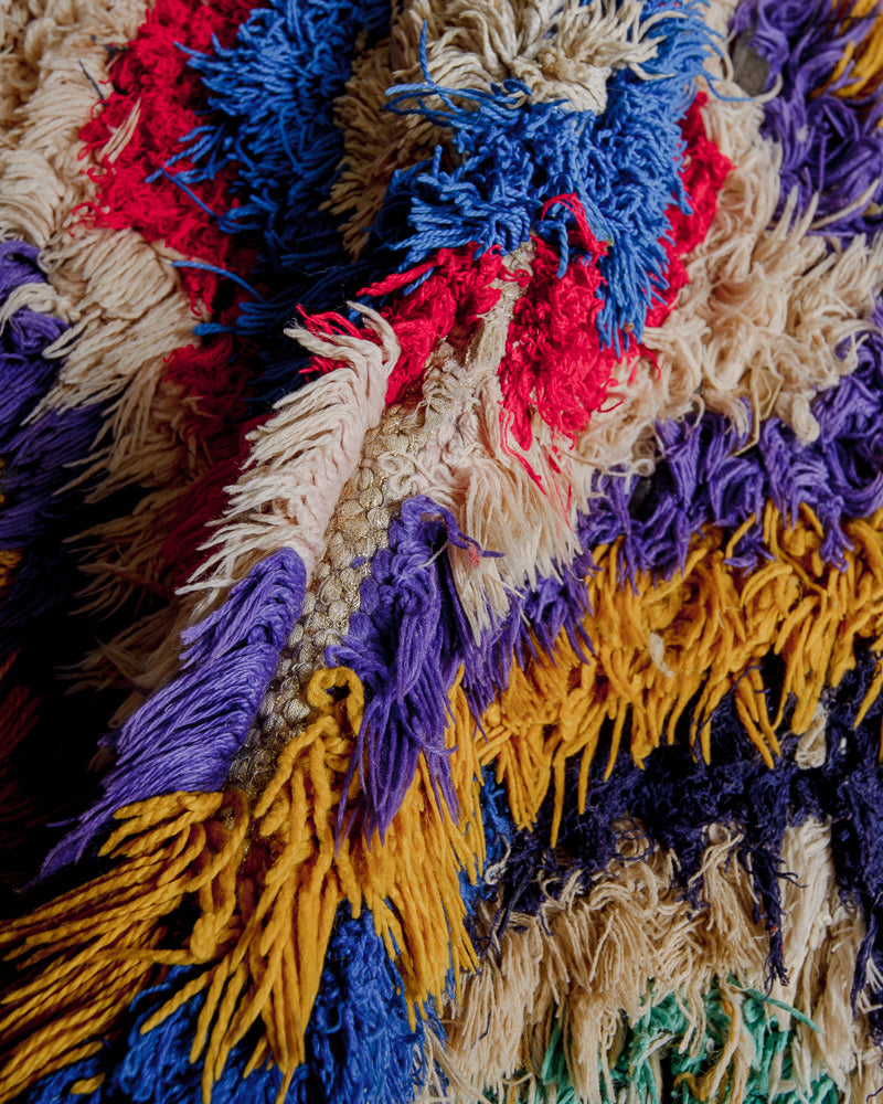 Close up of boucherouite rug with colourful cotton and fabric remnants and brown wool.