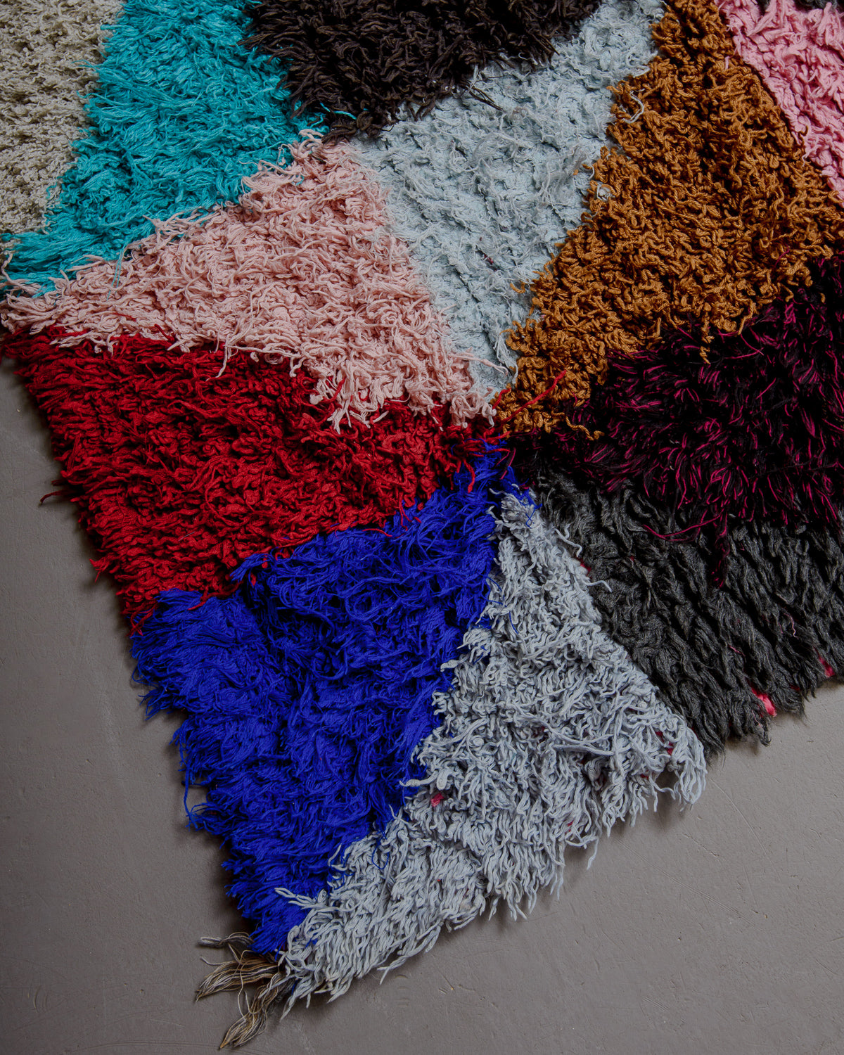 Corner of red , charcoal, blue and pink rug.