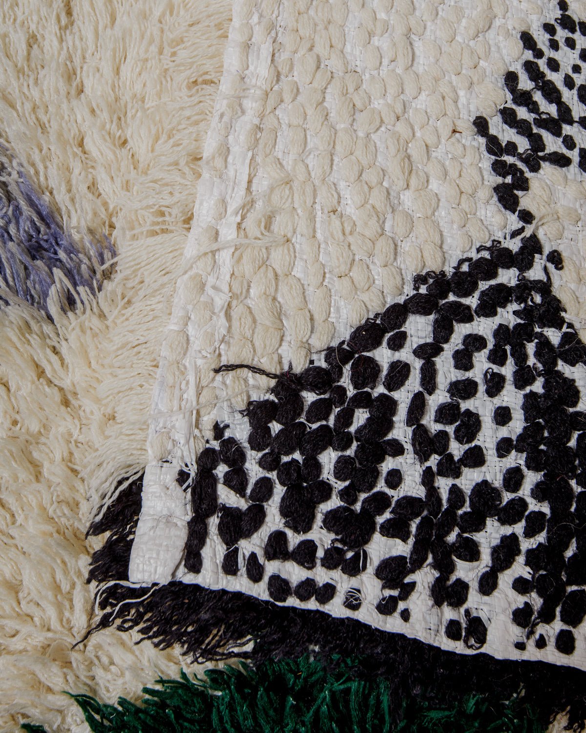 Close-up of boucherouite rug in black and cream with white plastic backing.