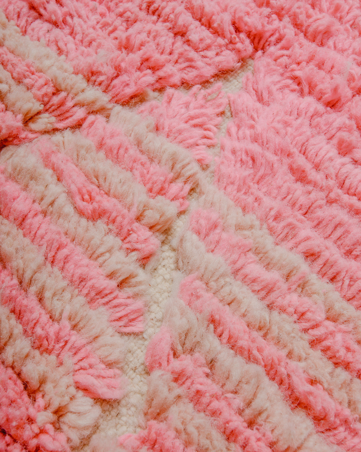 Surface of Boujaad runner rug showing two shades of pink in alternating rows and the tip of a woven diamond.