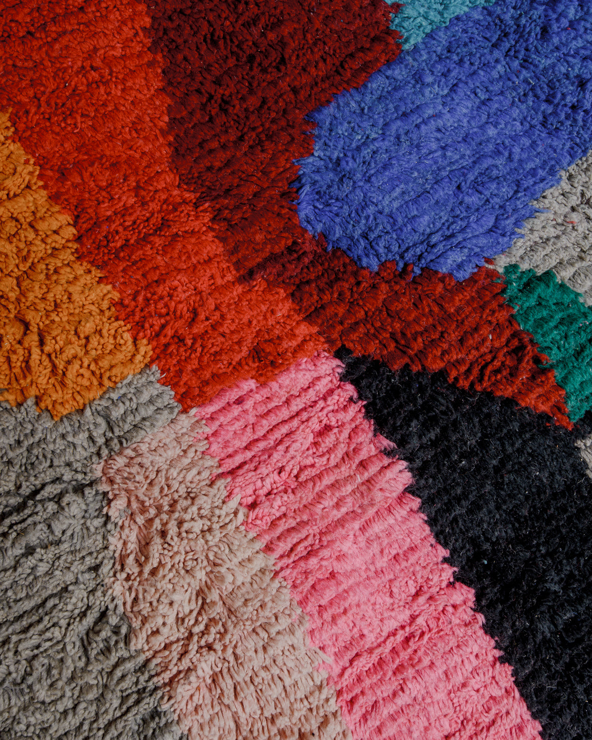 Surface of vintage wool rug with bold orange, red, blue, pink, green and grey