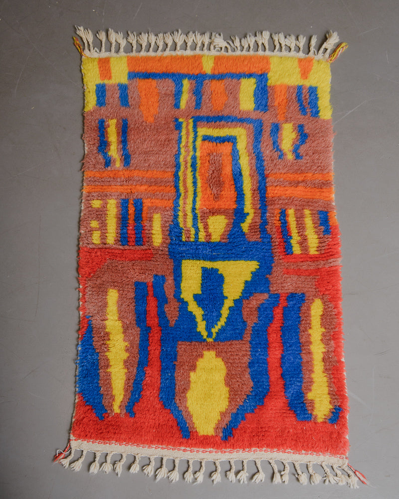 Colourful wool rug laying on a grey floor. 