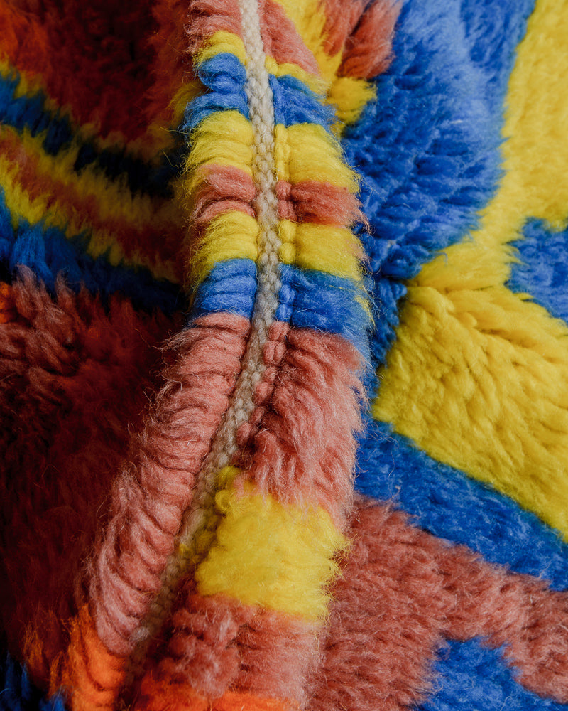 Close up of fluffy wool rug in blue, yellow, brown and orange. 
