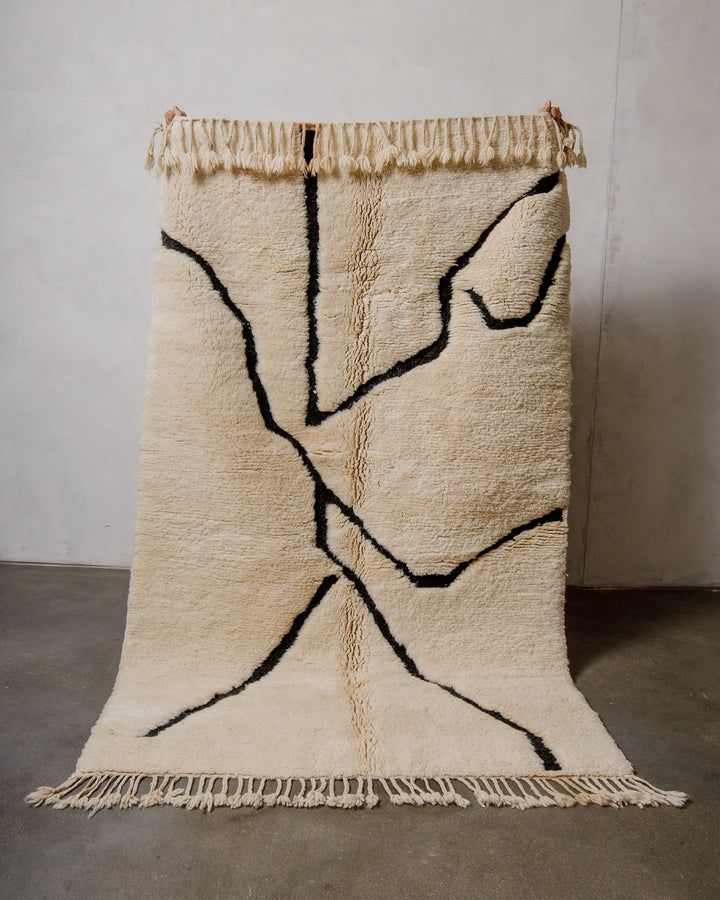 Beige and black abstract patterned rug on a plain background