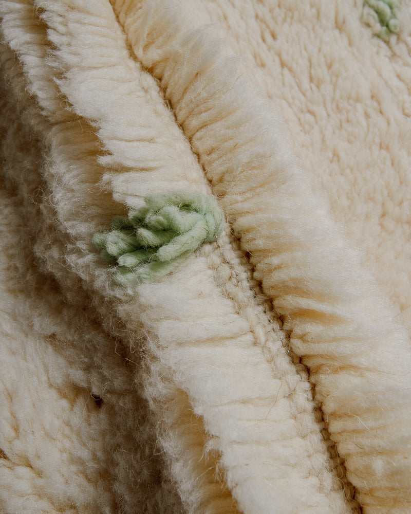 Close up of Berberlin Finest rug showing fluffy pile made of cream wool and soft green wool detail.
