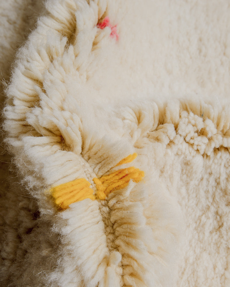 Close up of Berberlin Finest rug showing fluffy pile made of cream wool and yellow wool detail.