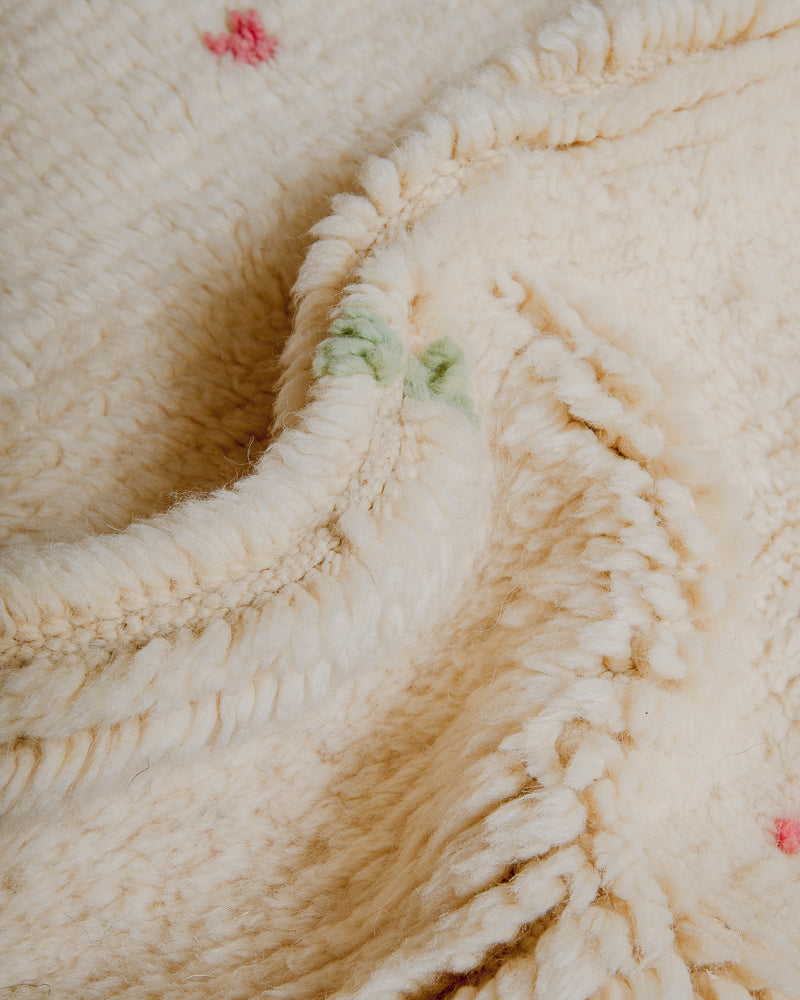 Close-up of cream wool rug with colourful dots.