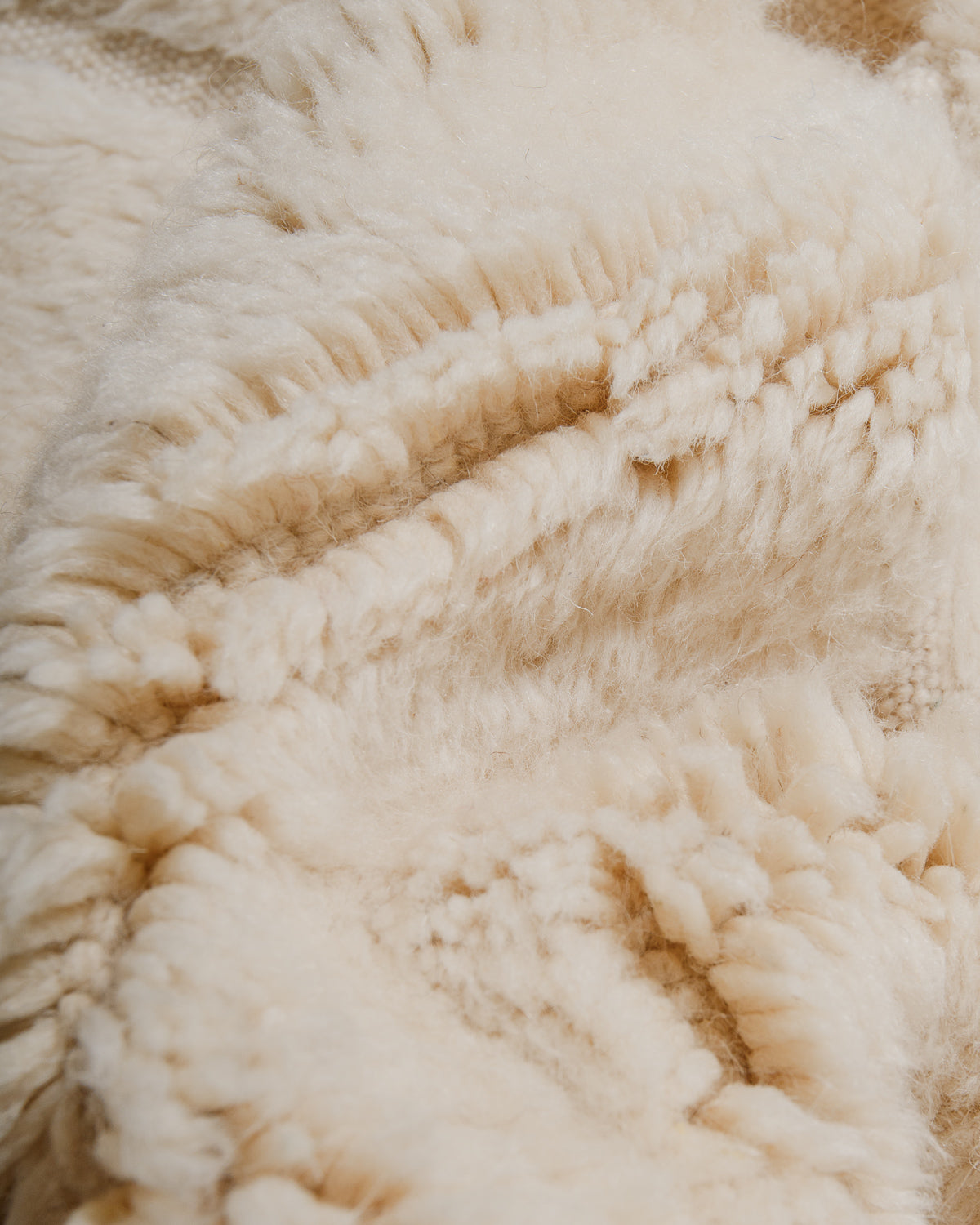 Close-up of a textured cream wool rug surface