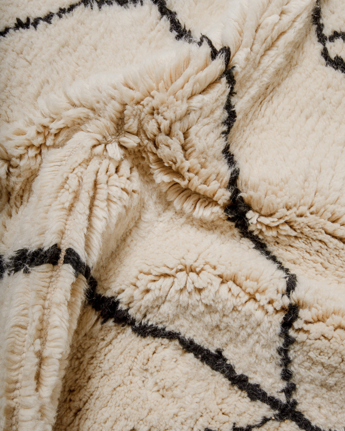 Close-up of a textured cream wool rug with black minimalist design