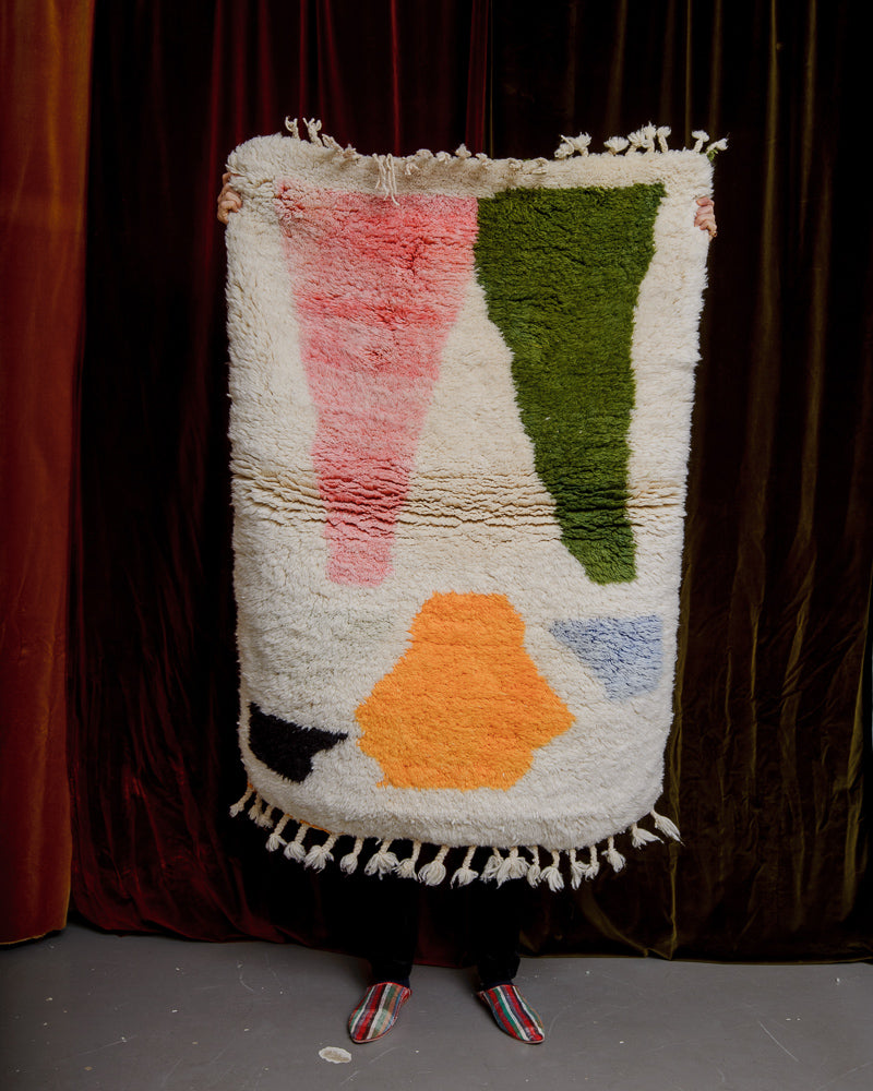 Wool rug being held in front of velvet curtains
