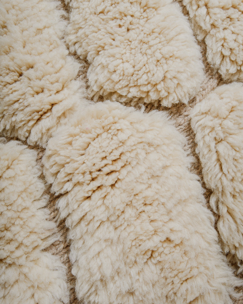 Surface or cream wool rug with woven patterns. 