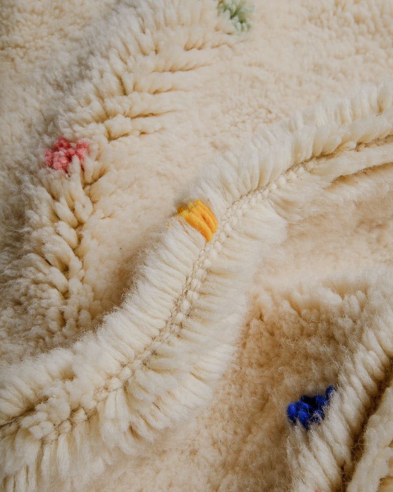 Close-up of cream wool rug with colourful dots.
