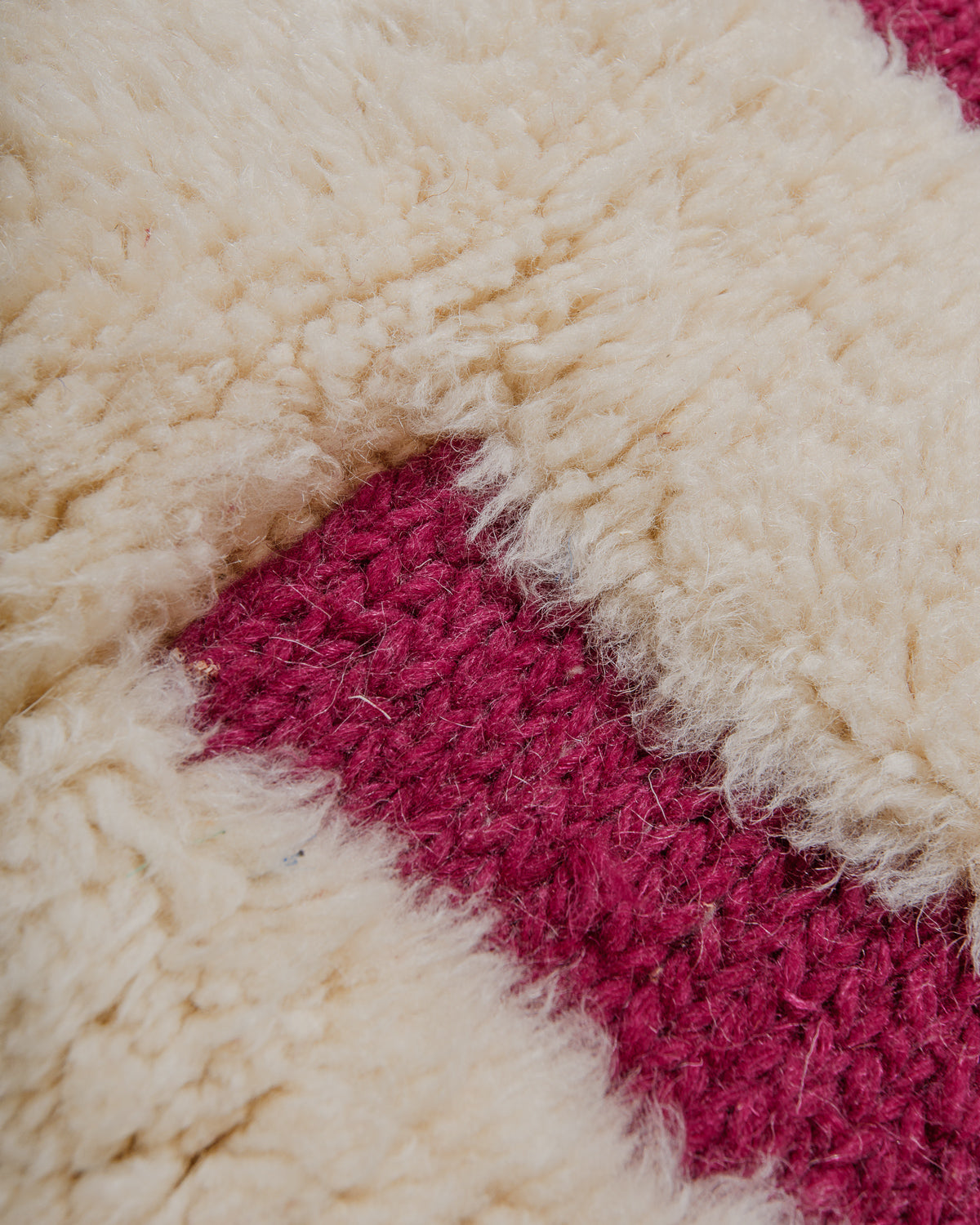 Close-up of a textured cream and magenta geometric patterned rug.