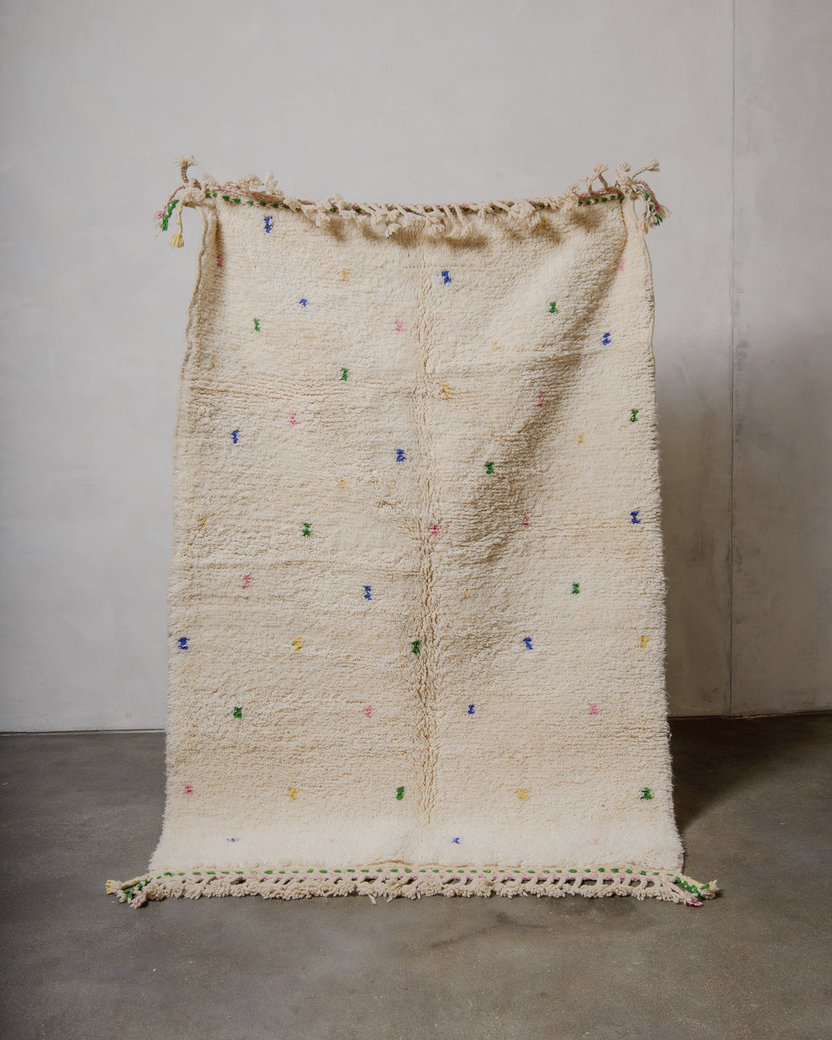 Textured rug with colorful specks on a plain background