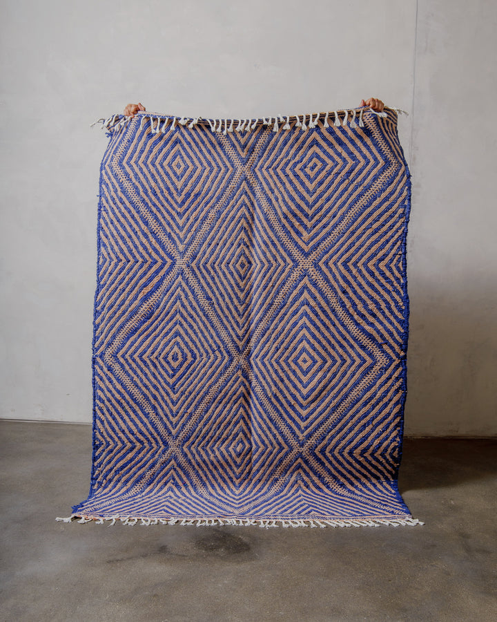 Blue and pink geometric patterned rug on a plain background