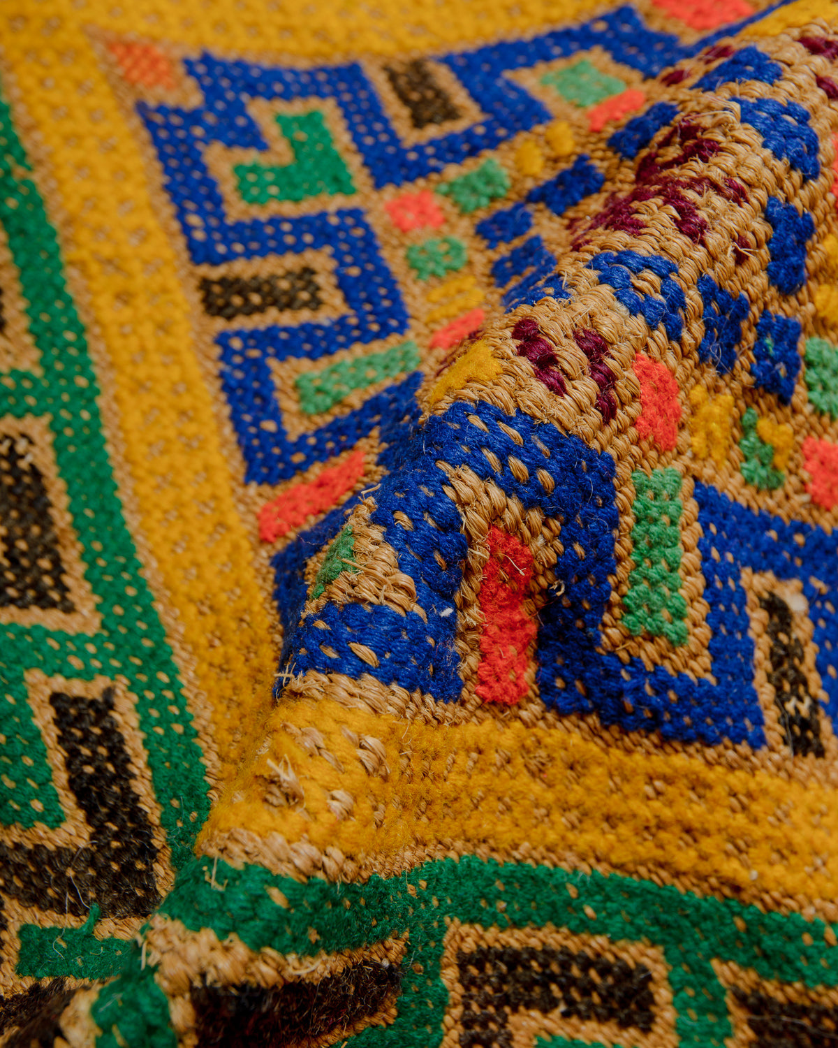 Close up of Vintage Kelim rug in bright yellow, orange, blue and green. The rug is made of colourful cotton and wool and straw. 
