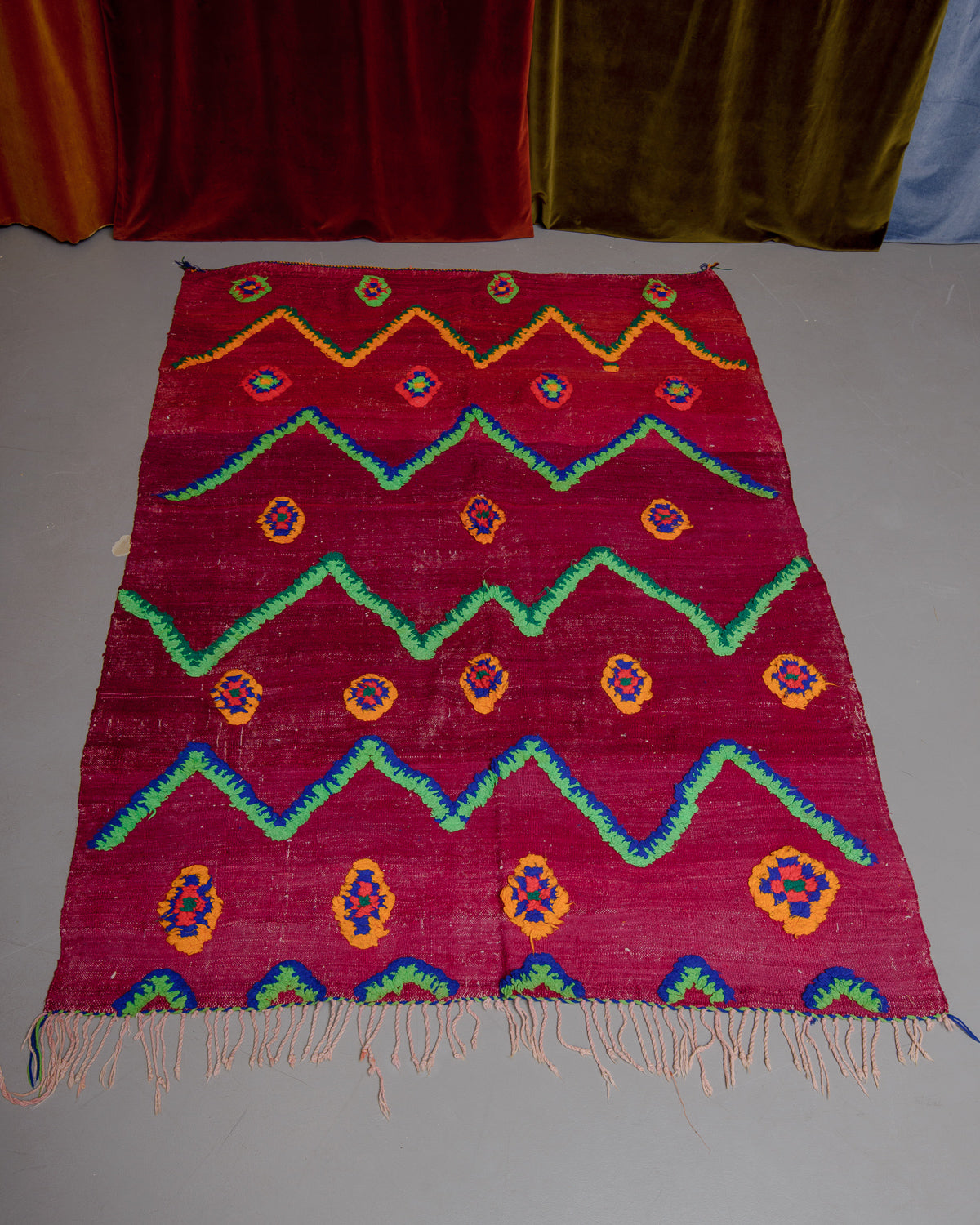 Vintage Kelim rug in bright red, green, orange and blue on grey floor. 