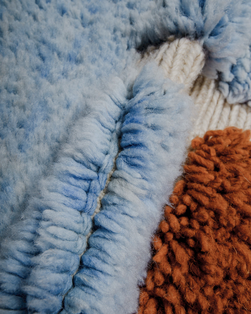 Close up of blue and brown mrirt rug with cream fente. 