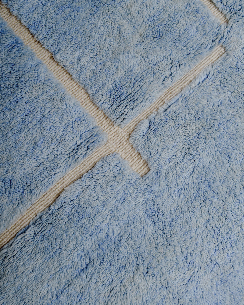 Surface of blue Mrirt rug with cream woven line design.