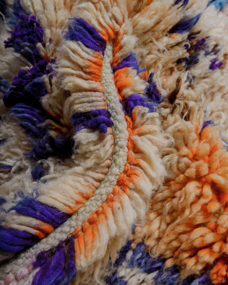 Close-up of a fluffy wool rug with orange, purple, and beige colours.
