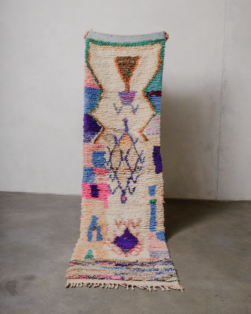Colorful geometric-patterned rug on a plain floor with a white wall background