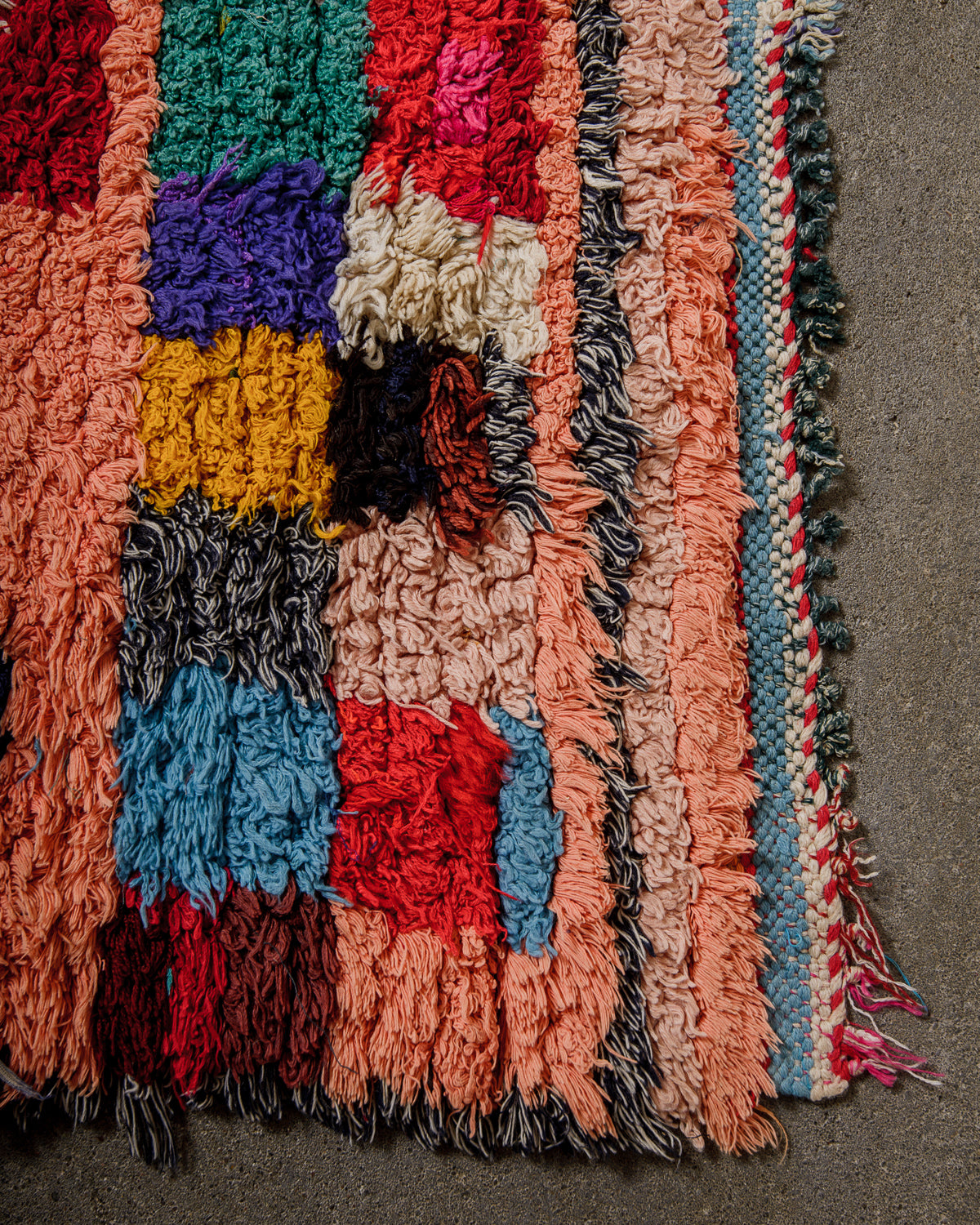 Multicoloured textured rug with short fringes on a concrete floor