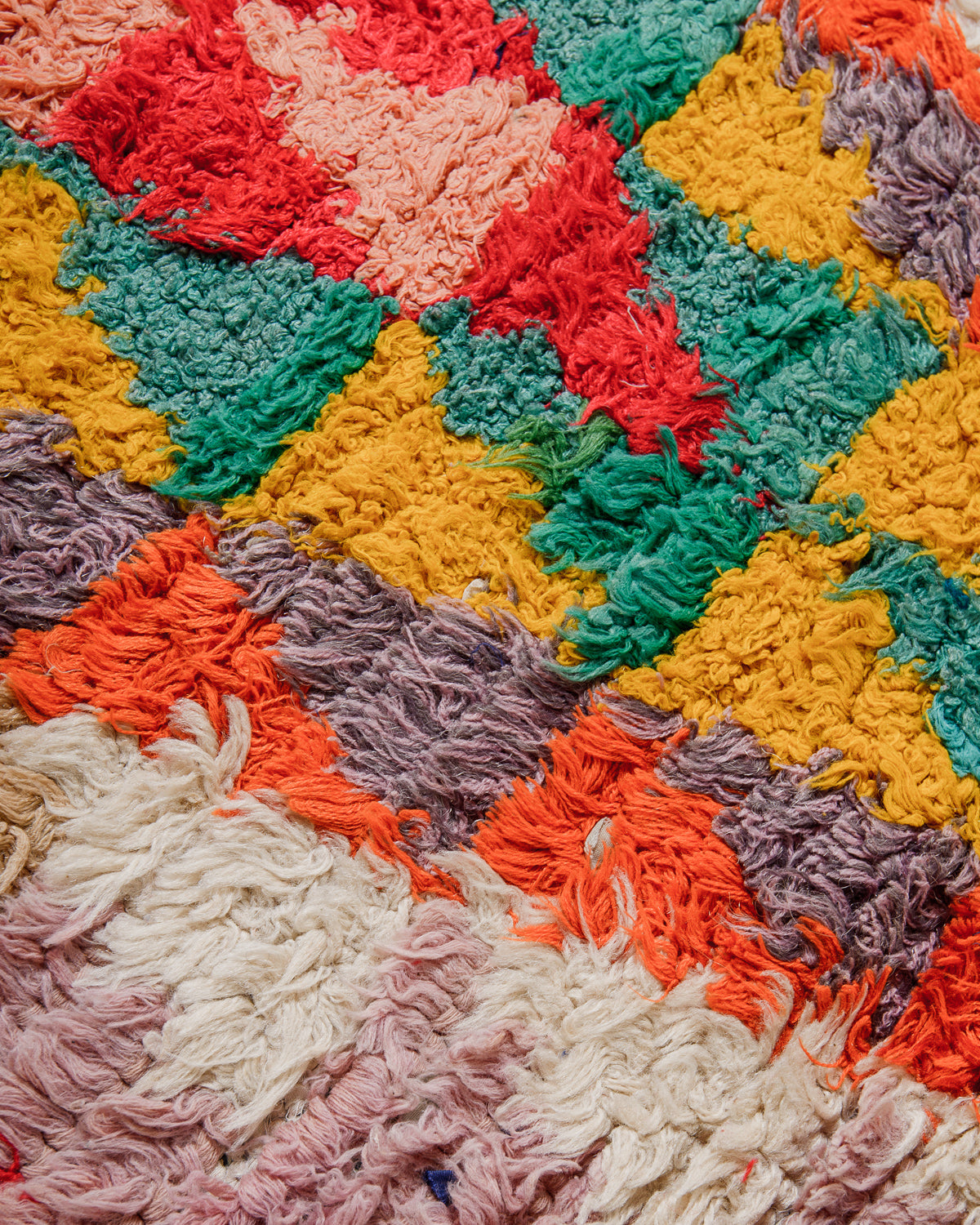 Close-up of a colorful textured fabric rug with a triangle pattern.