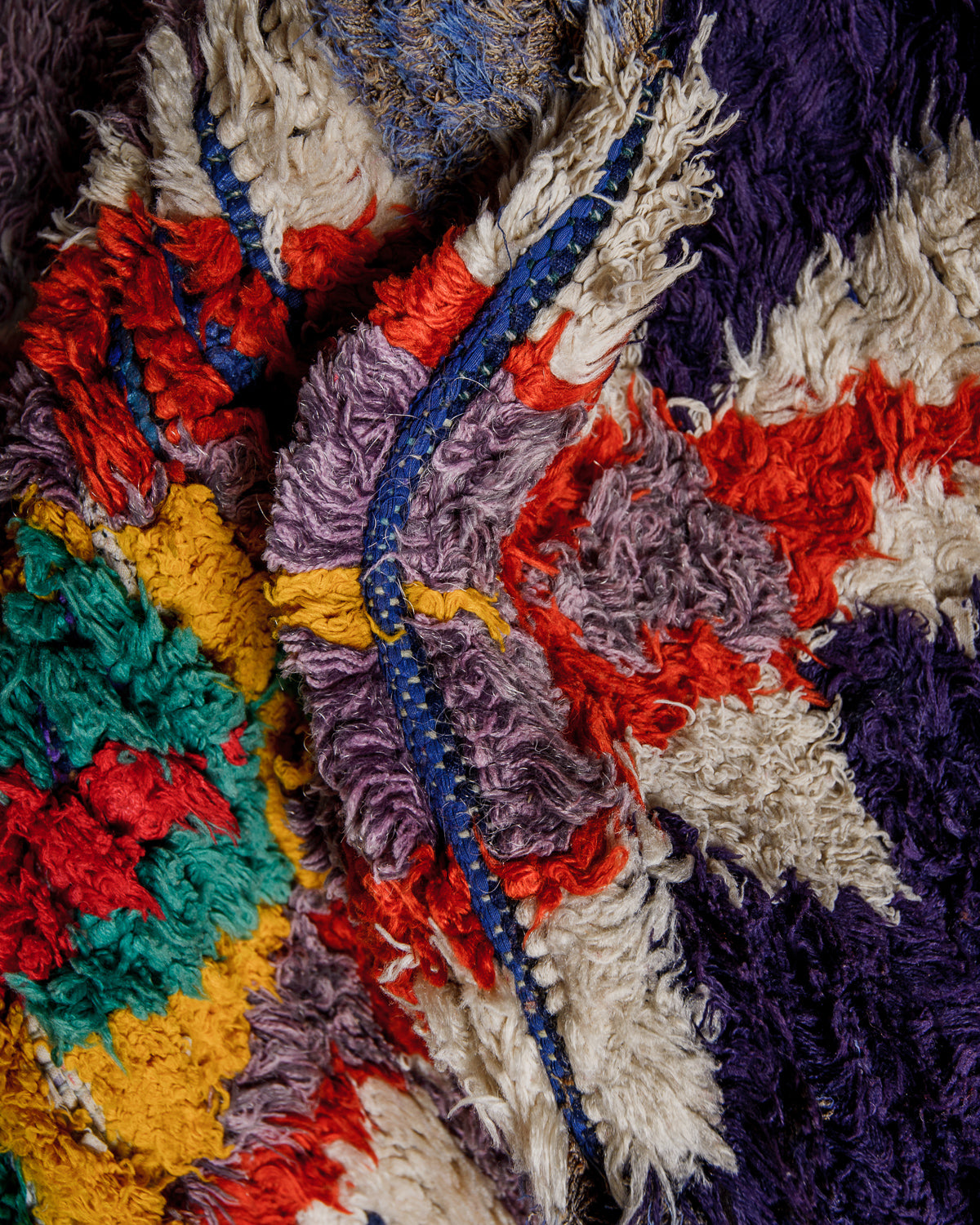 Close-up of a colourful textured rug with various patterns and colours.