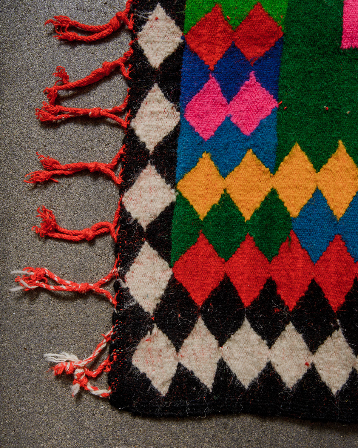 Colorful geometric patterned rug with tassels on a dark surface