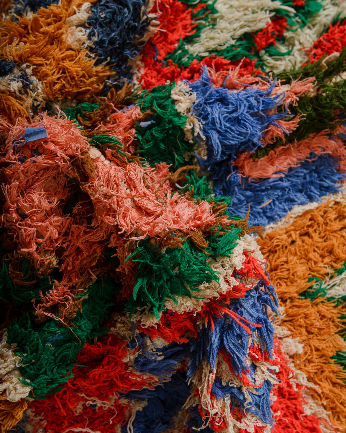 Close-up of a colourful textured fabric with various colours including orange, blue, red, and green.